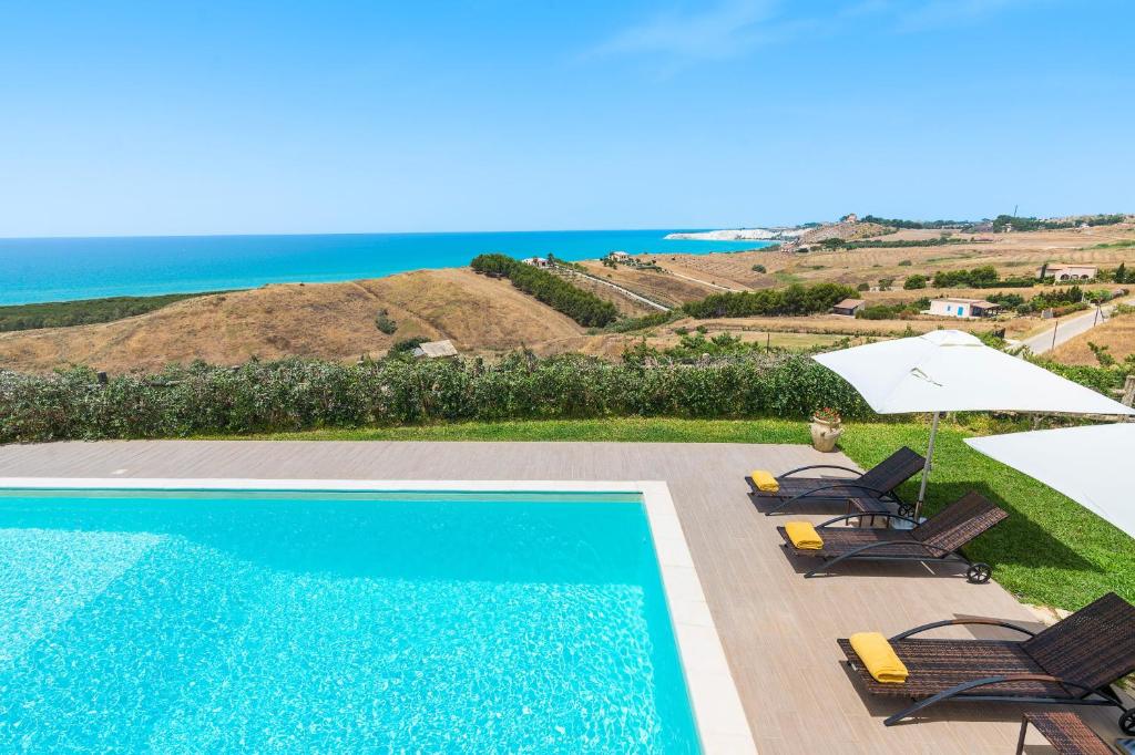 a swimming pool with chairs and an umbrella and the ocean at Villa Anthea in Montallegro