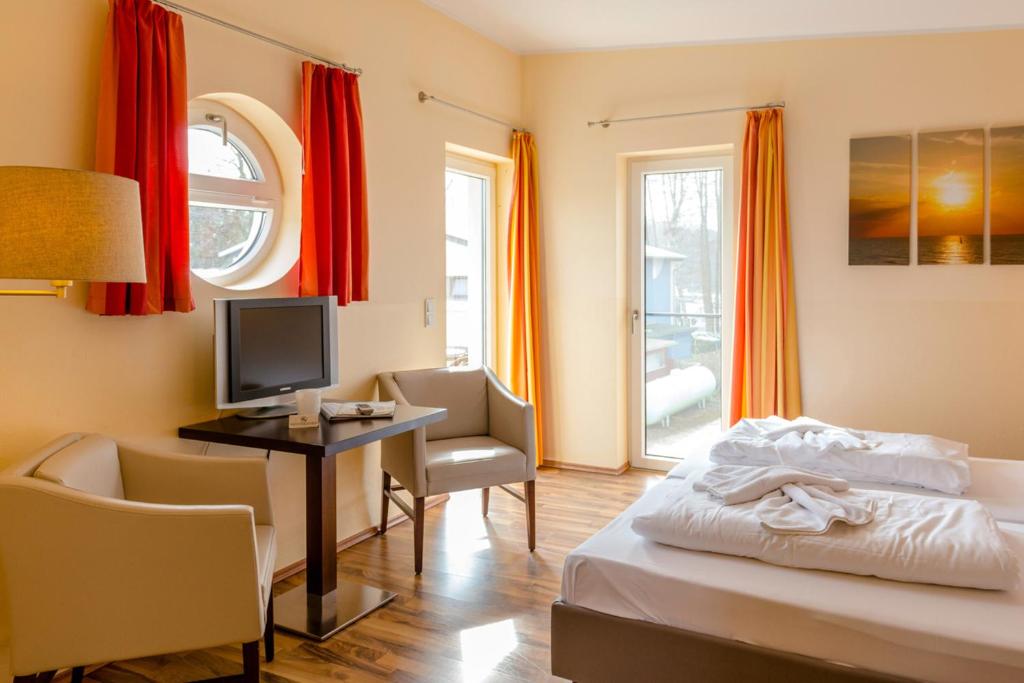 una camera d'albergo con letto e scrivania con TV di Fleesensee 02 a Eldenburg