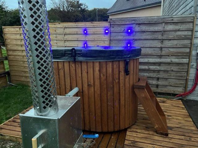 einen Whirlpool auf einer Holzterrasse mit lila Lichtern in der Unterkunft Cottage cocooning romantique avec jaccuzzi privé in Ancinnes