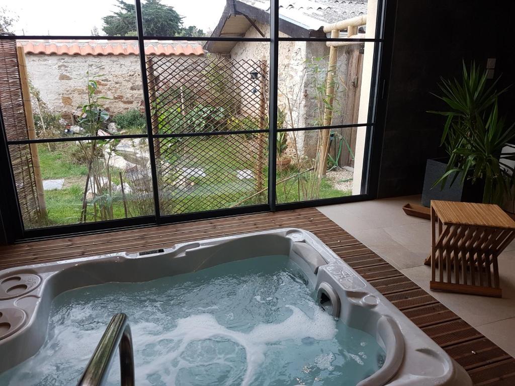 détente gite et spa entre mer et marais في Bourgneuf-en-Retz: حوض استحمام ساخن في غرفة مع نافذة