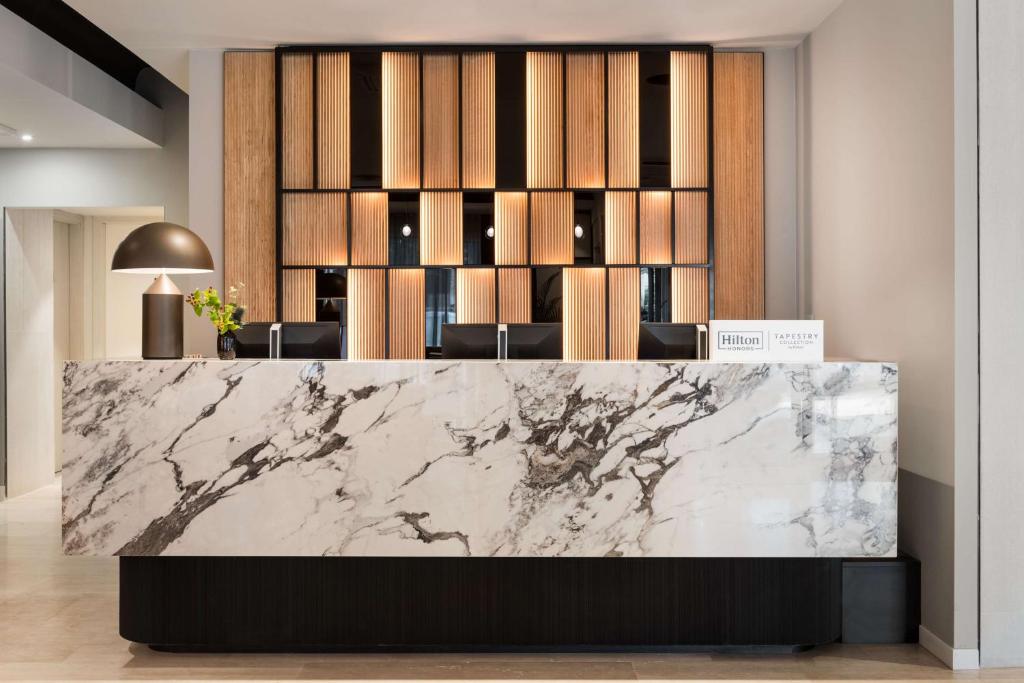 a lobby with a marble counter and chairs at Tapestry by Hilton Ambasciatori Hotel in Mestre