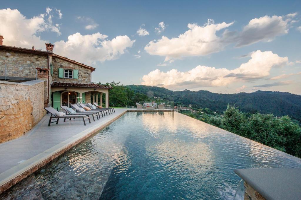 una piscina con sillas y una casa en Villa Grema, a Farmhouse with Infinity Pool, en Loppeglia
