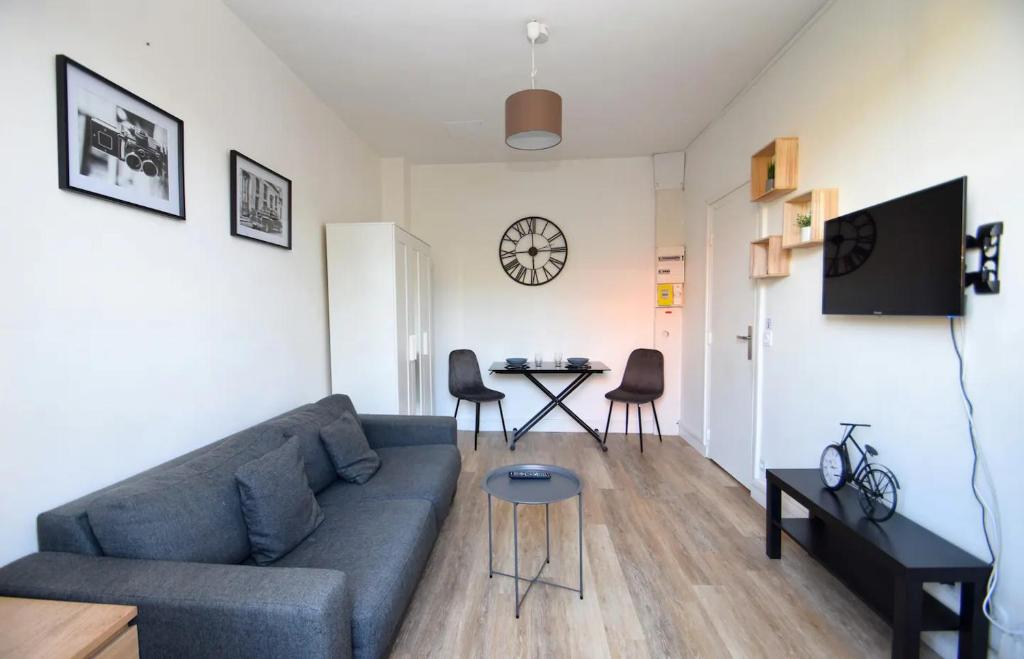 a living room with a couch and a table at Superbe studio 2 pers tout équipé WIFI & Proche Paris - R2 in Montreuil