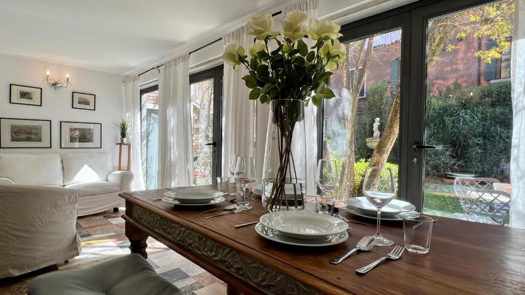 una sala de estar con una mesa con un jarrón de flores en Residence Flowery en Venecia
