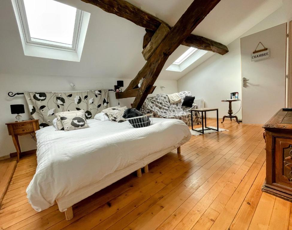 a bedroom with a large white bed and wooden floors at Les Mirabelles in Tournon-dʼAgenais