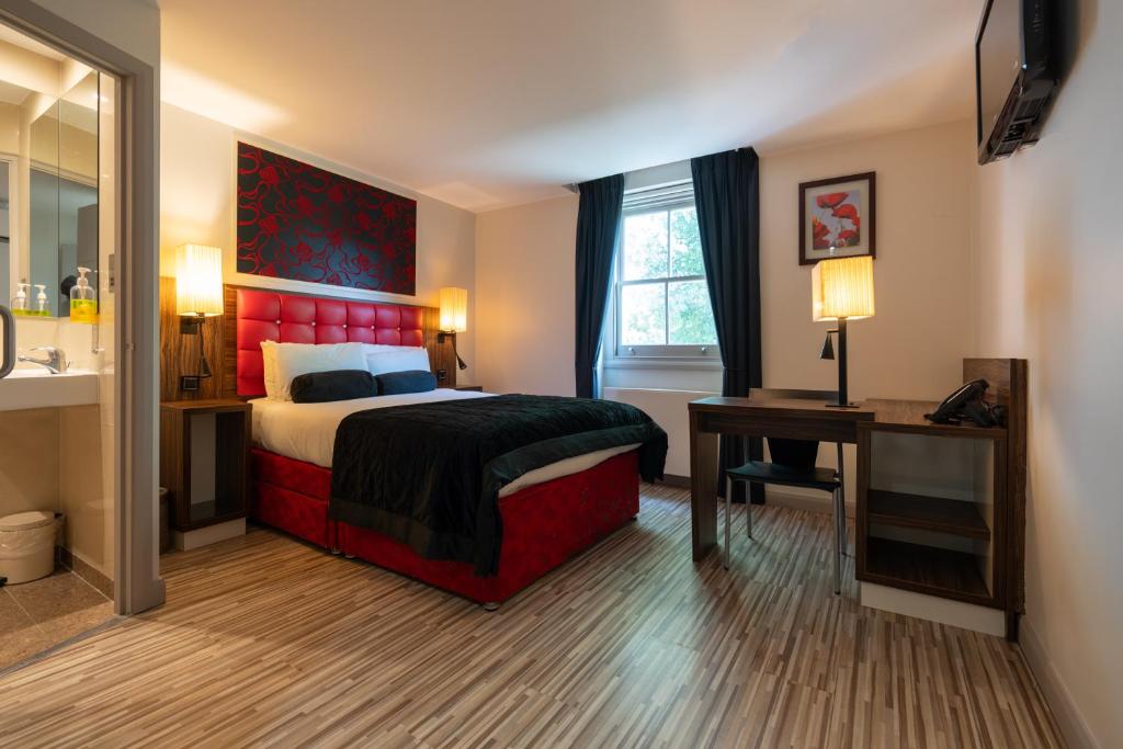 Schlafzimmer mit einem Bett, einem Schreibtisch und einem Spiegel in der Unterkunft Simply Rooms & Suites in London