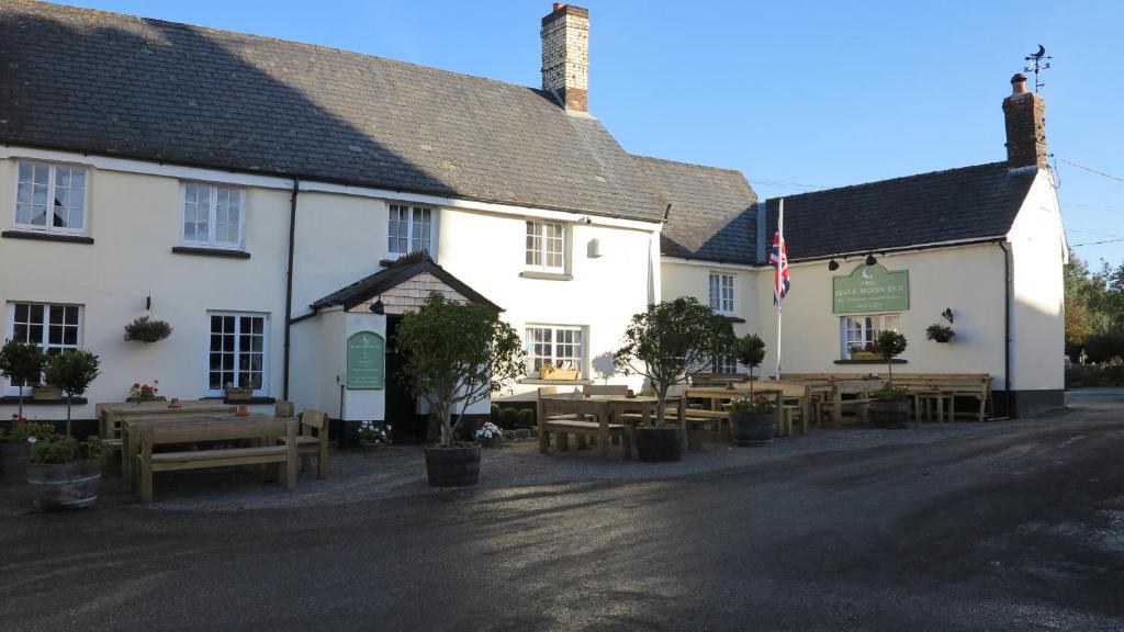 a white building with tables and benches in front of it at Half Moon Inn in Sheepwash