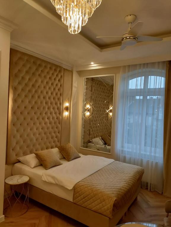 Schlafzimmer mit einem Bett, einem Fenster und einem Kronleuchter in der Unterkunft Crystal in Zielona Góra
