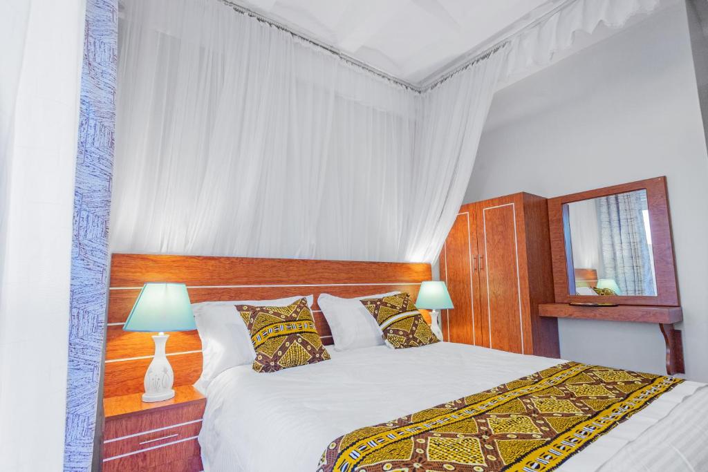 a bedroom with a white bed with a wooden headboard at Ambrosia Heights in Entebbe