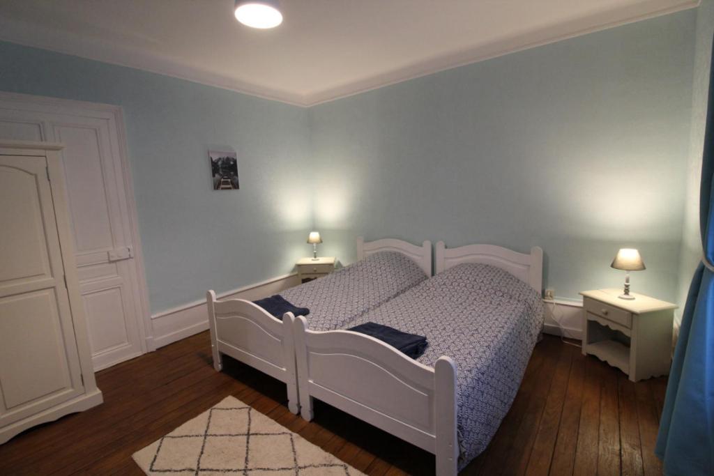ein Schlafzimmer mit einem weißen Bett und zwei Nachttischen in der Unterkunft Appartement dans Maison in Plainfaing