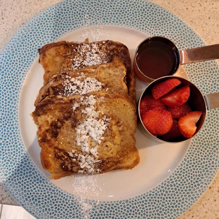 a plate with french toast and a bowl of strawberries at Waterfront House in Dartmouth