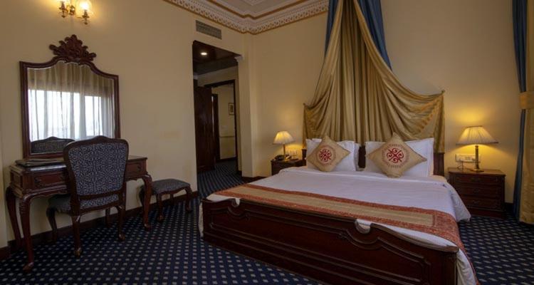 a hotel room with a large bed and a desk at Hotel Dynasty in Guwahati