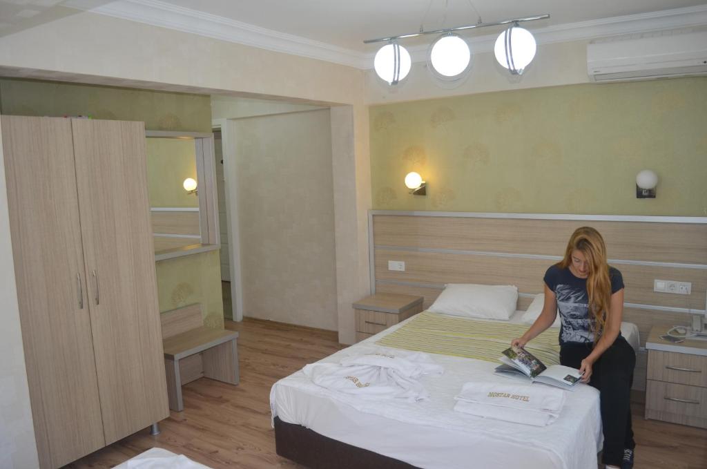 une femme debout sur un lit dans une pièce dans l'établissement Mostar Hotel, à Ayvalık