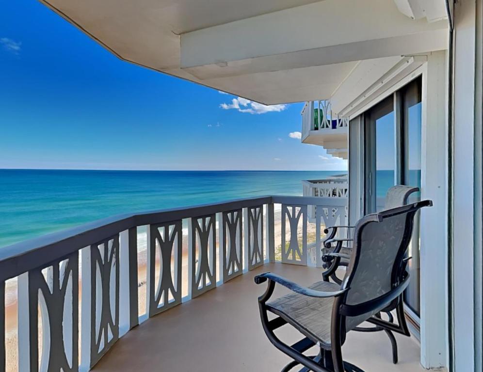 a balcony with two chairs looking out at the ocean at Oceanside Retreat 804 in Ormond Beach