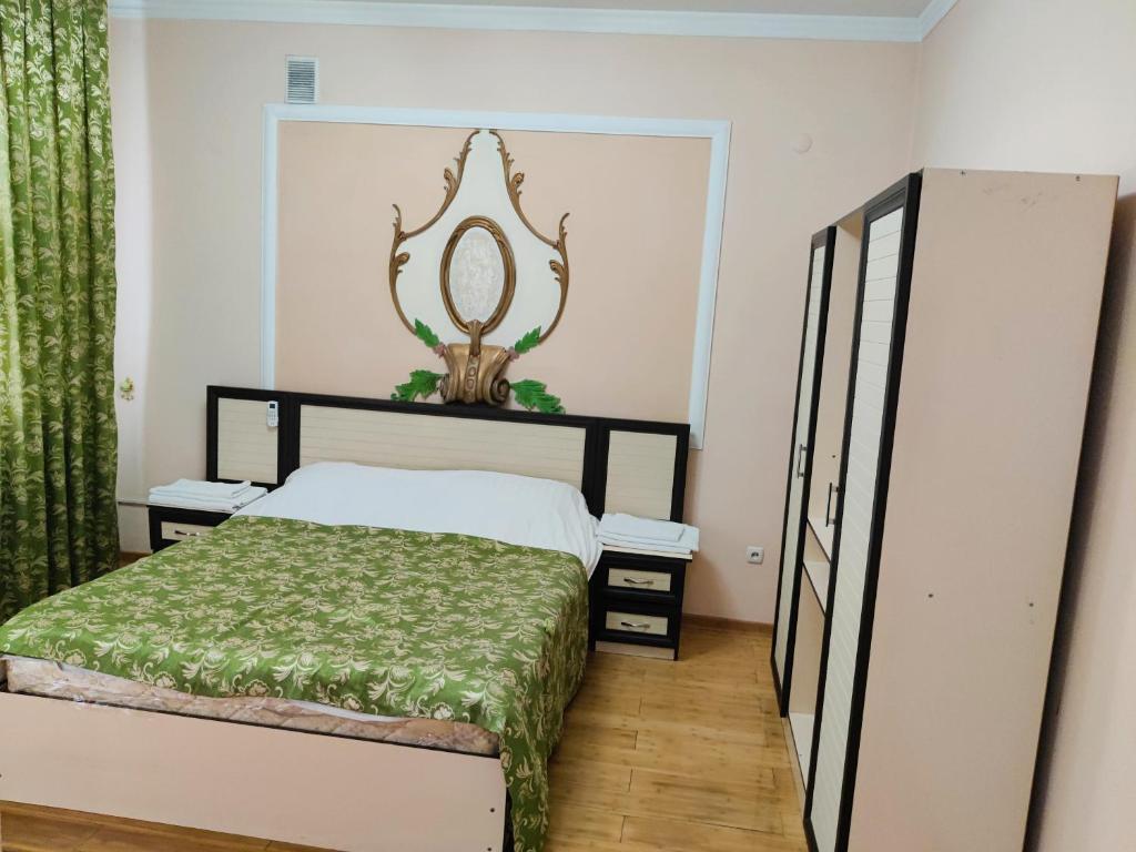 1 dormitorio con cama y espejo en la pared en Hotel Zavq, en Andiján