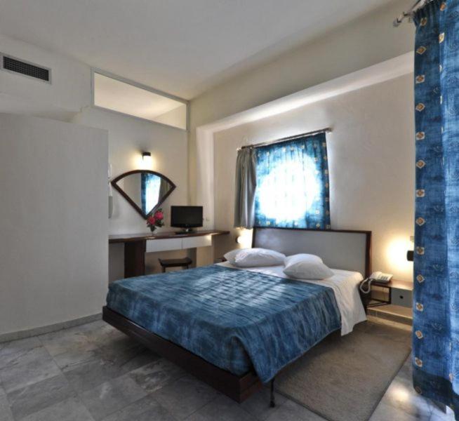 a bedroom with a bed and a desk and a window at Rodon Hotel in Chania
