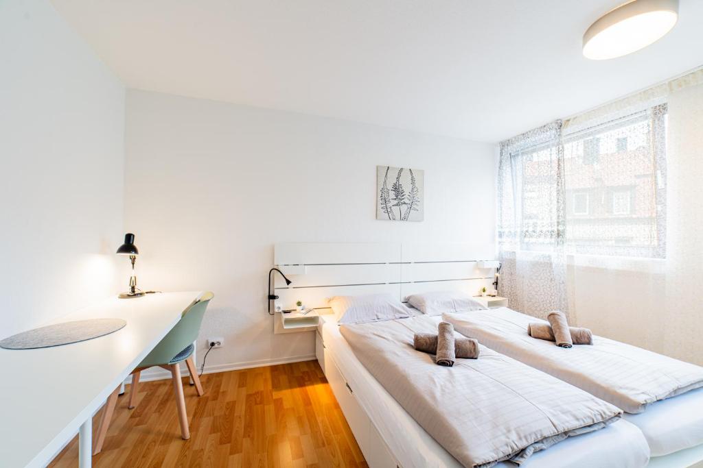 2 bedden in een witte kamer met een bureau en een raam bij Modern und Renoviert in Neurenberg