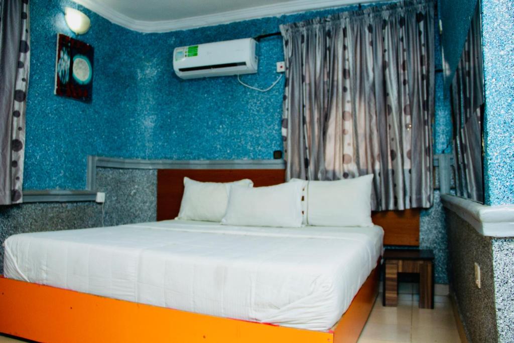 1 dormitorio con 1 cama con pared azul en Double One Suites & Lodge, en Ikeja
