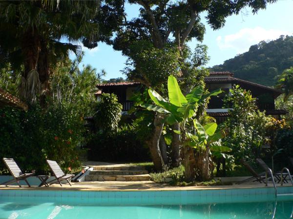 een huis met 2 stoelen en een zwembad bij Hotel Eco Sítio Nosso Paraíso in Saquarema