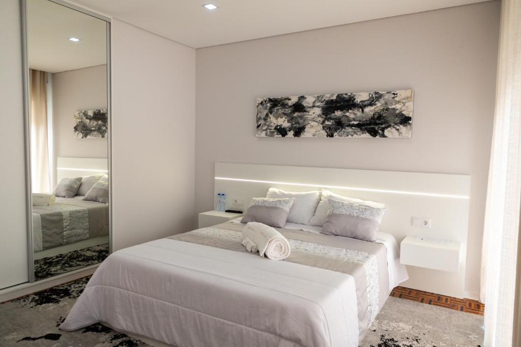 biała sypialnia z łóżkiem i lustrem w obiekcie Refúgio do Mar w mieście Aguçadoura