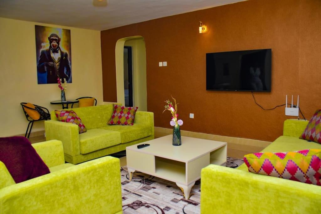 sala de estar con sofás amarillos y TV en The Green Baroness, en Eldoret