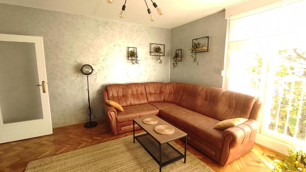 ein Wohnzimmer mit einem braunen Ledersofa und einem Tisch in der Unterkunft Apartman Majur in Slavonski Brod