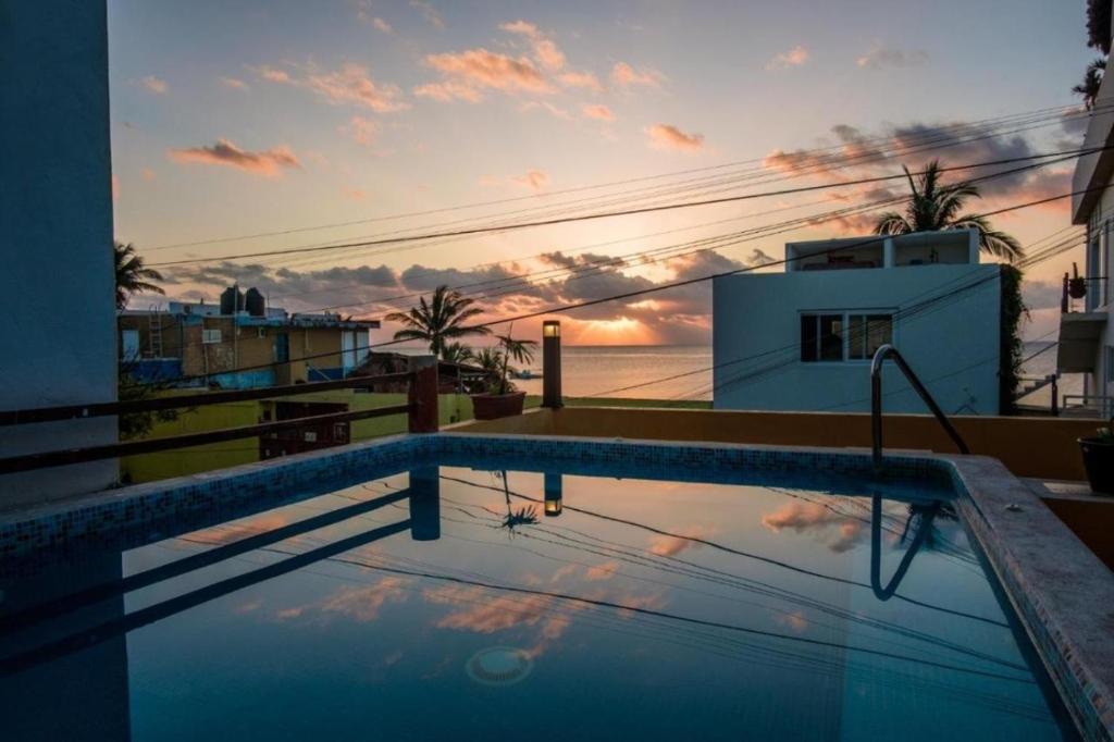 a swimming pool on the roof of a building with a sunset at Casa Velero Puerto Morelos in Puerto Morelos