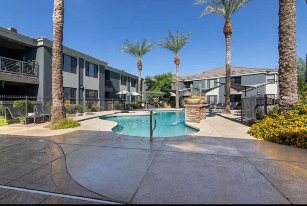 a swimming pool with palm trees in front of a building at Modern 2BR Oasis! in Phoenix