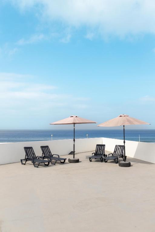 a group of chairs and umbrellas on a beach at Refúgio do Mar in Aguçadoura