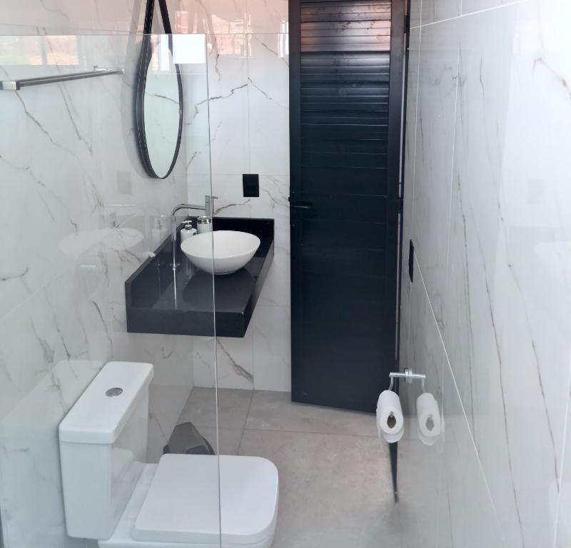 a bathroom with a toilet and a sink and a mirror at B&B Pousada Swiss Residence in Aquiraz
