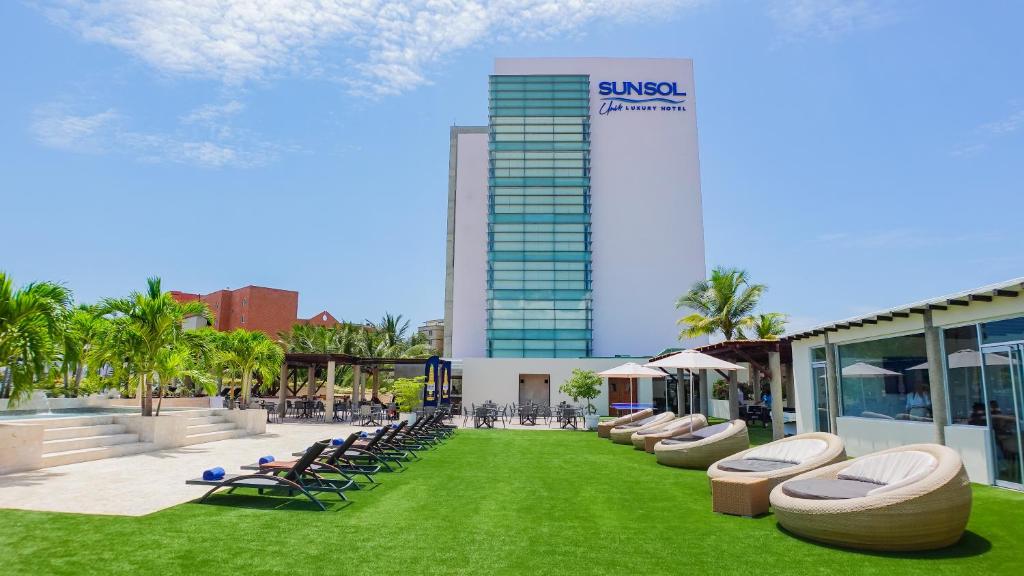 - un bâtiment avec des chaises longues et une pelouse devant dans l'établissement SUNSOL UNIK Luxury Hotel, à Porlamar