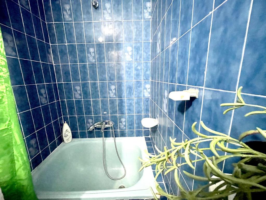a blue tiled bathroom with a tub and a plant at Room near the beach for 2 in Valencia
