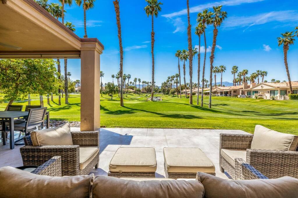 a patio with a table and chairs and palm trees at Beautiful Condo with Mountain & Sunset Views! in Palm Desert