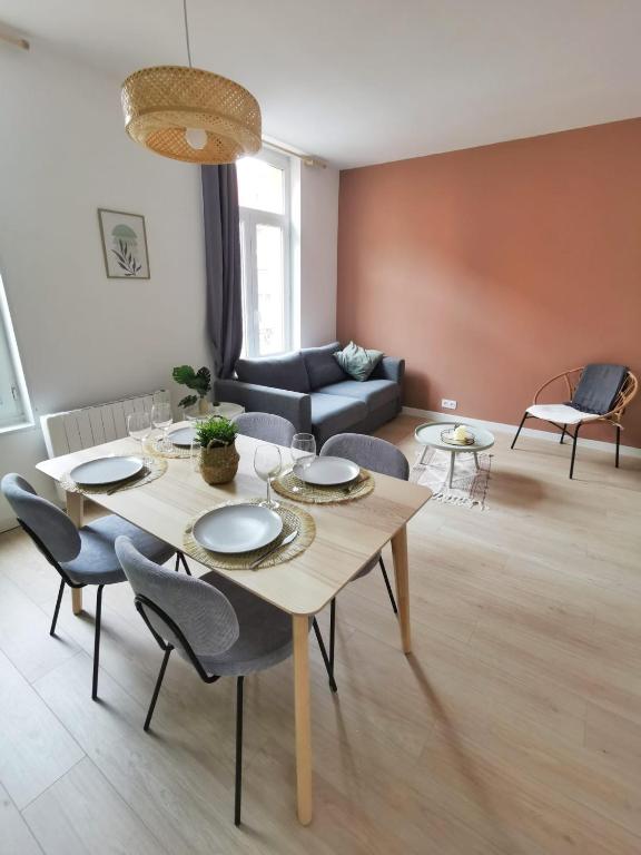 een woonkamer met een tafel en stoelen en een bank bij Le Bohème (Centre - Gare - Commerces) in Lens