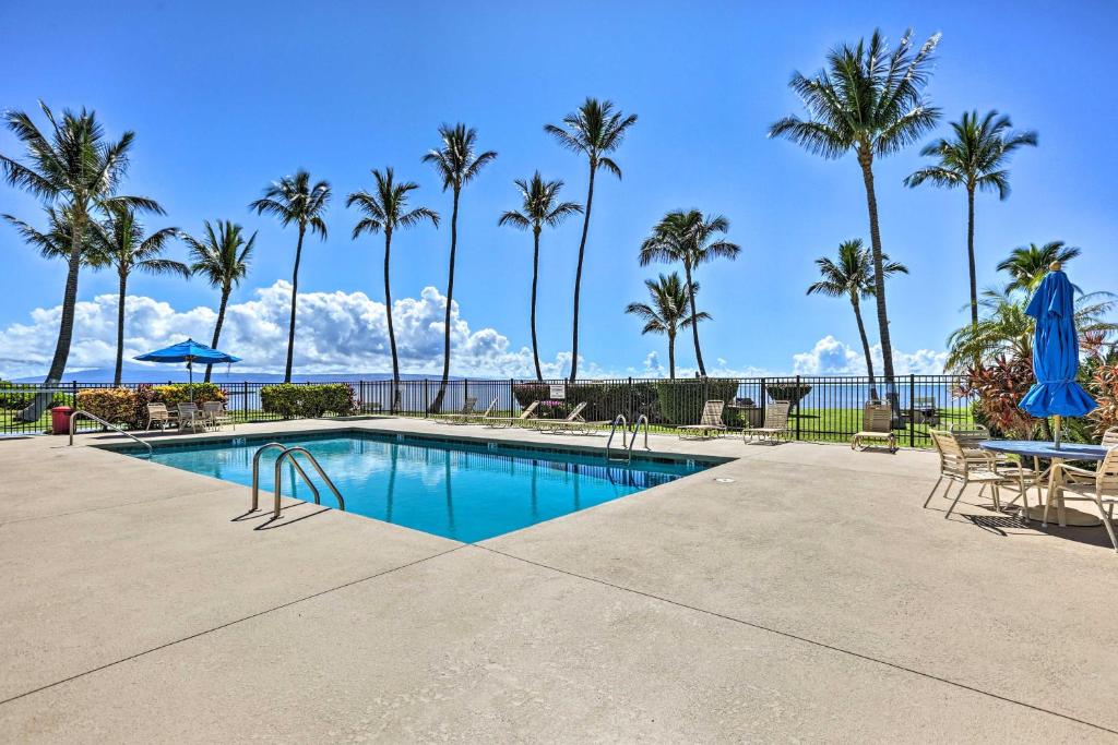 una piscina con palme, tavolo e sedie di Kaunakakai Condo Walk to Beach, Community Pool! a Kaunakakai