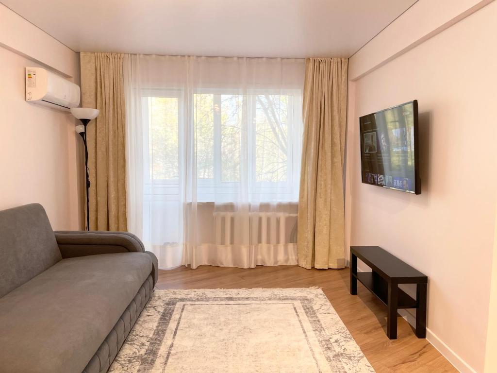 - un salon avec un canapé et une fenêtre dans l'établissement Apartment Dzerzhinskogo, à Öskemen