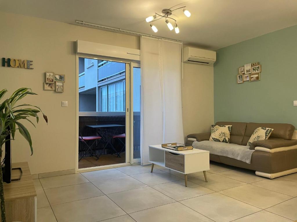 a living room with a couch and a table at Appartement calme, climatisé 3min à pied de la mer in Palavas-les-Flots