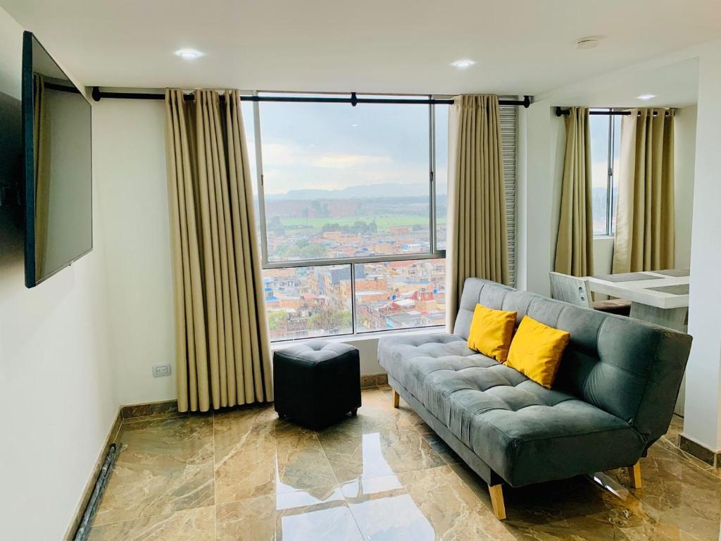 a living room with a couch and a large window at Alquiler Apartamento en Bogotá cerca al aeropuerto-Colibri Dorado in Bogotá