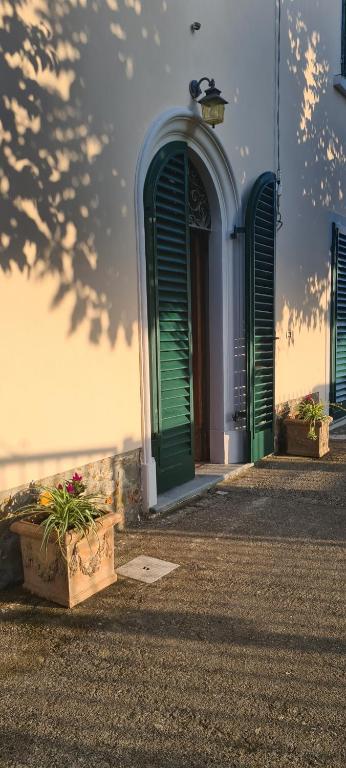 a building with green doors and some flowers in a box at La Tana di Ulisse in Borgo a Buggiano