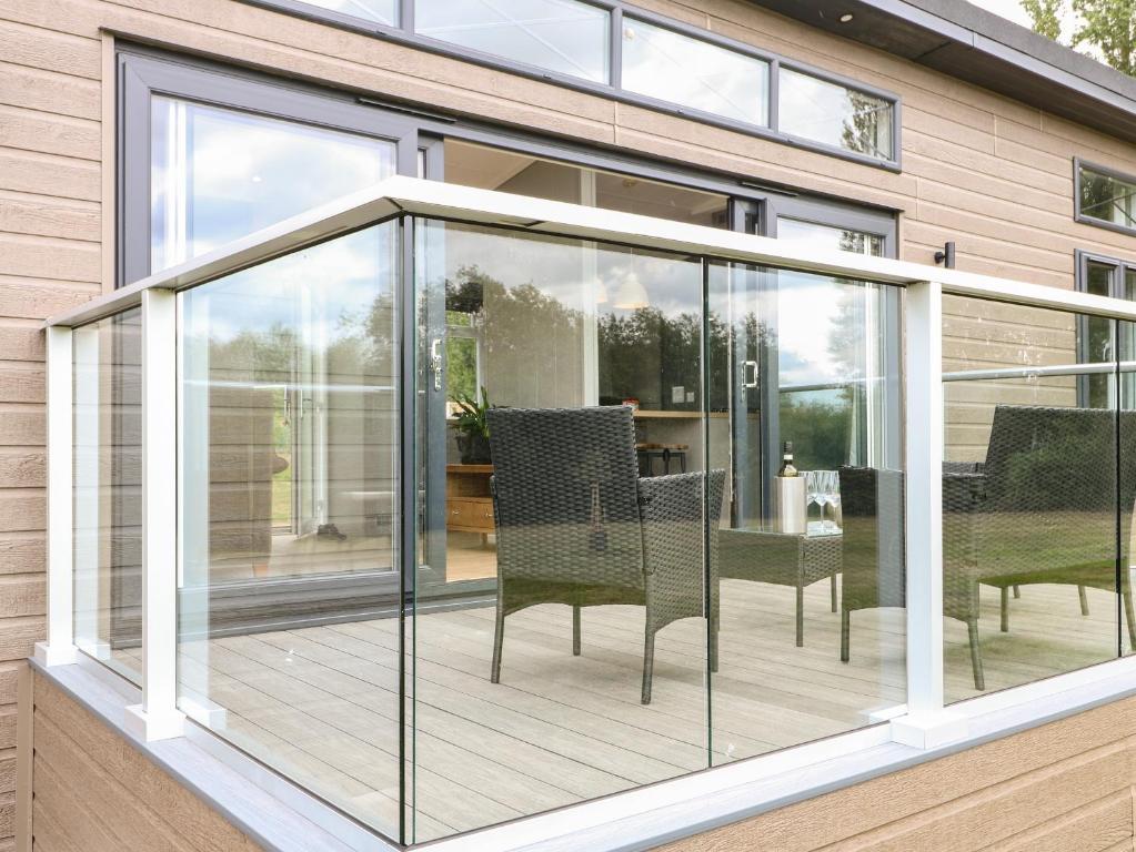 a glassconservatory with chairs and tables on a deck at Willow Lodge in Newark upon Trent