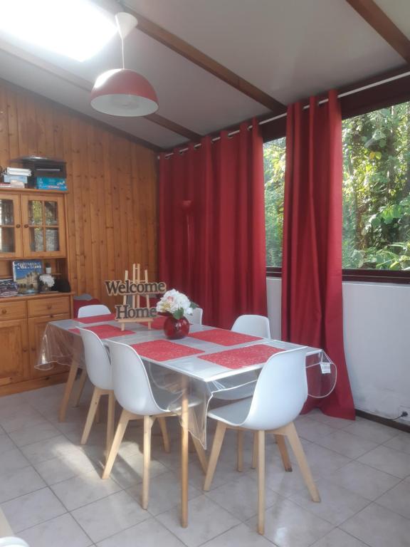 stół jadalny z białymi krzesłami i czerwoną zasłoną w obiekcie maison village 4 chambres 30 minutes du zoo de beauval w mieście Saint-Cyran-du-Jambot