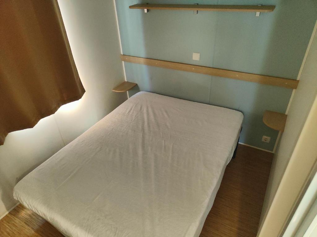 Mobil-home في فالراس بلاج: غرفة نوم صغيرة مع سرير أبيض في غرفة