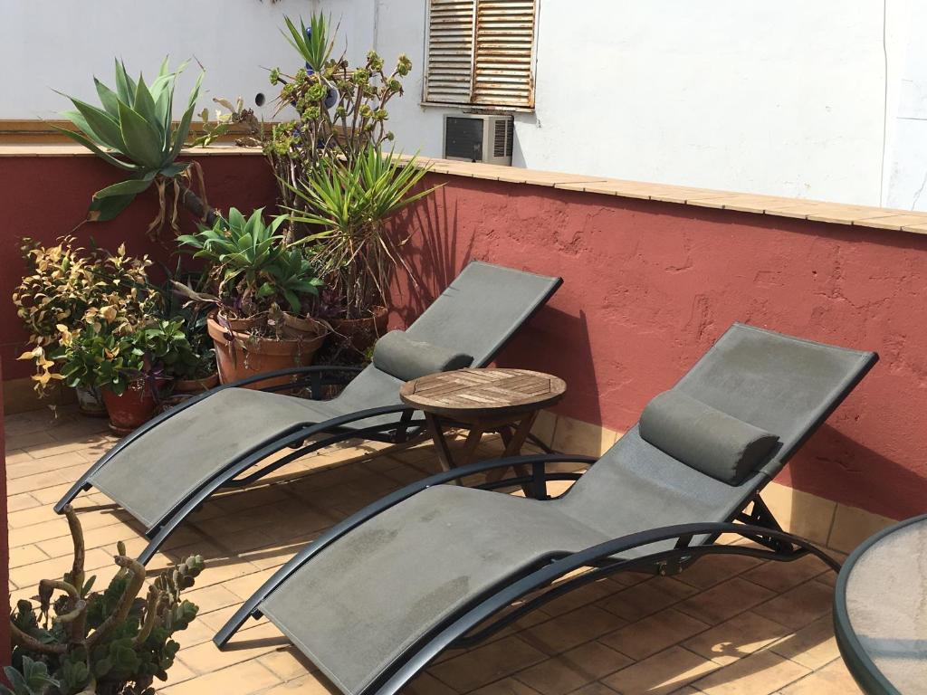trzy krzesła i stół na patio w obiekcie Casa Sevillana w Sewilli