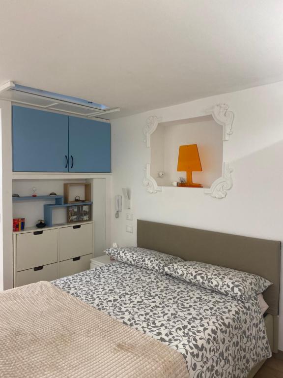 a white bedroom with a bed and a orange lamp at Silvano Cozy Loft in Bologna