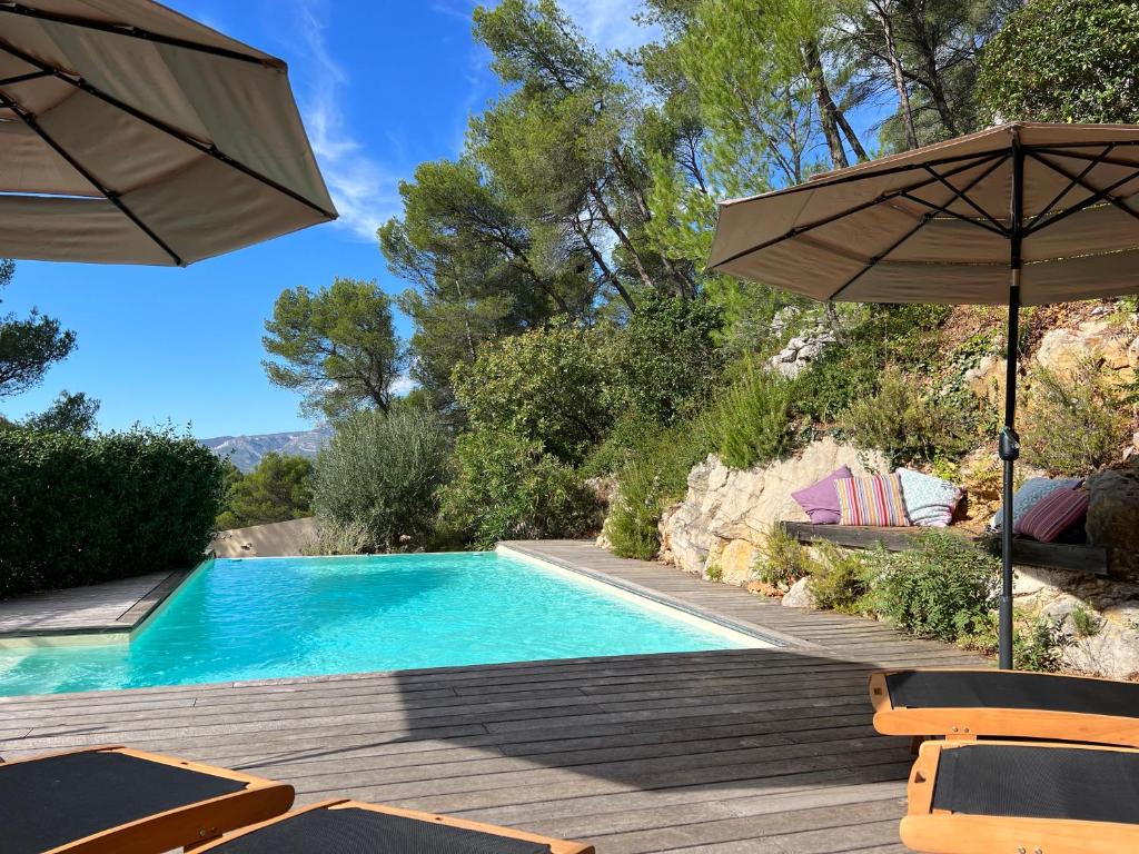 a swimming pool with an umbrella and chairs next to it at B&B Les Têtes de Mules - Adults Only in Gémenos