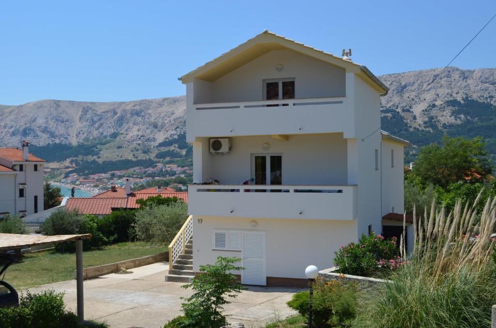 a white house with a mountain in the background at Apartments Ivana in Baška