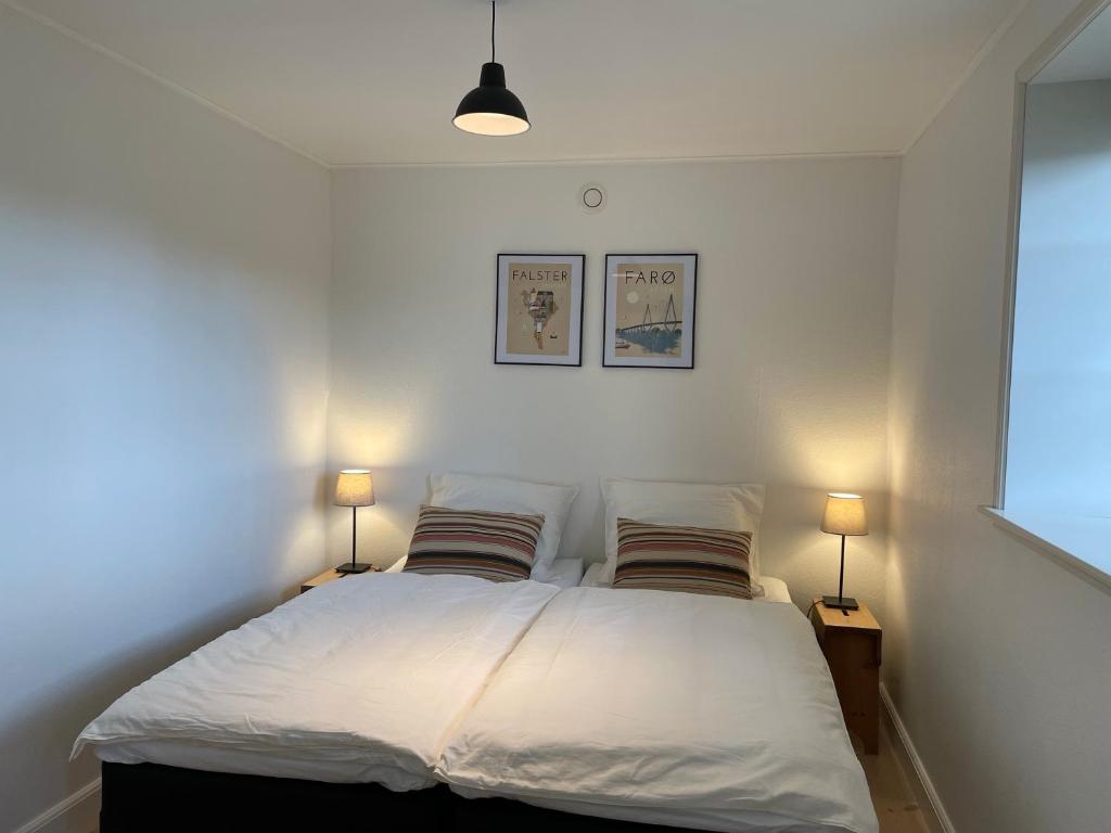 a bedroom with a bed with two lamps on both sides at Strandby 1847 B&B in Nykøbing Falster