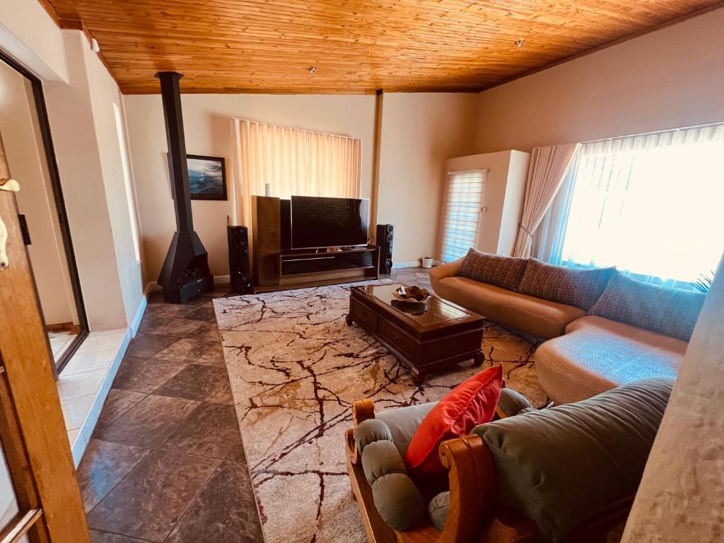 a living room with a couch and a tv at Langerman Lookout: Inviting Home with Rustic Charm and Modern Comfort in Johannesburg