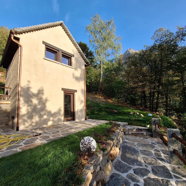 una casa con una pasarela de piedra junto a un edificio en Baita Dinh - Villaggio dei Crodini en Crodo