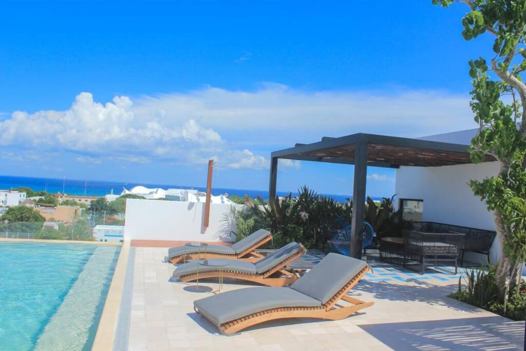 a row of lounge chairs next to a swimming pool at Luxury apartament 1 block to 5Th Avenue in Playa del Carmen